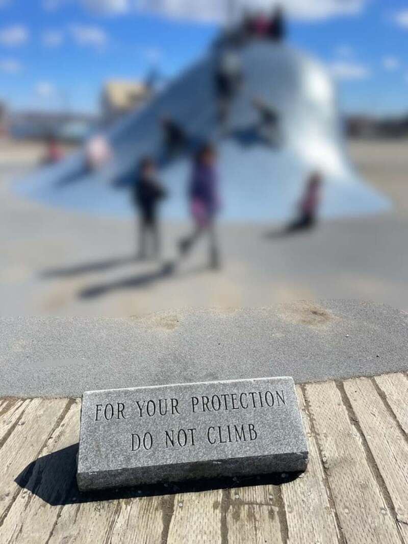 Stone with inscription 'FOR YOUR PROTECTION DO NOT CLIMB' in front of a large snow sculpture.