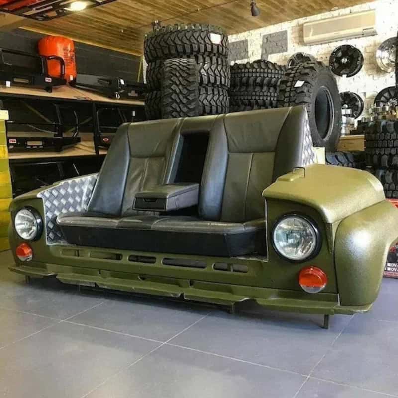 Unique sofa designed to look like a green off-road vehicle with tires in the background.