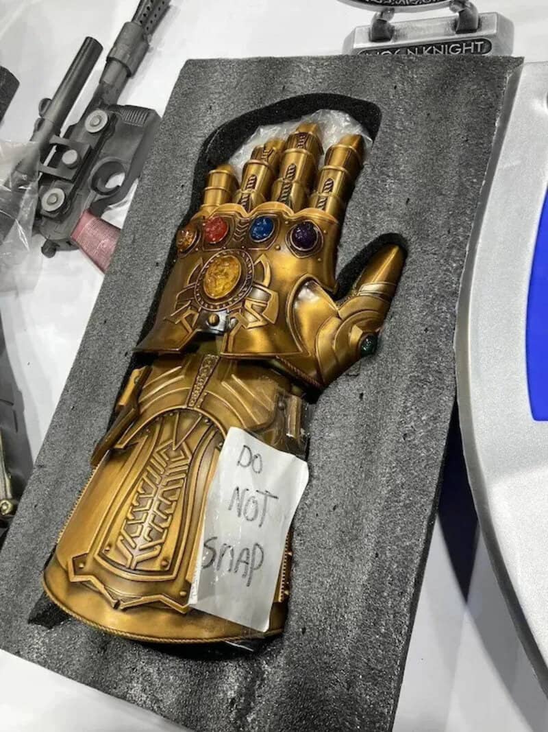 Golden Thanos glove with a note saying 'Do Not Snap' on it.