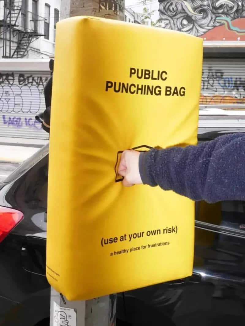 Public punching bag on city street with a person's fist punching it.