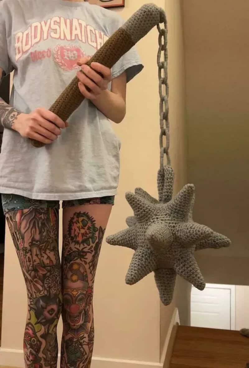 Person holding a spiked star-shaped object attached to a chain.