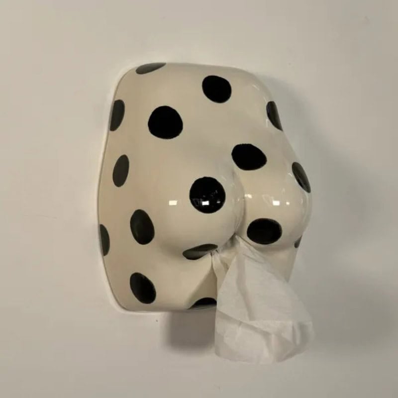 Polka dot tissue dispenser on wall with tissue hanging out.