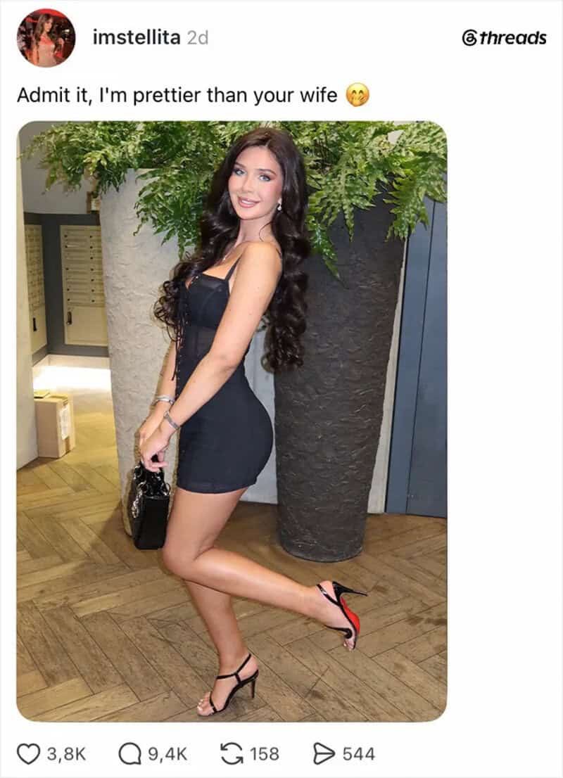 Woman in black dress and heels posing indoors with greenery behind her.