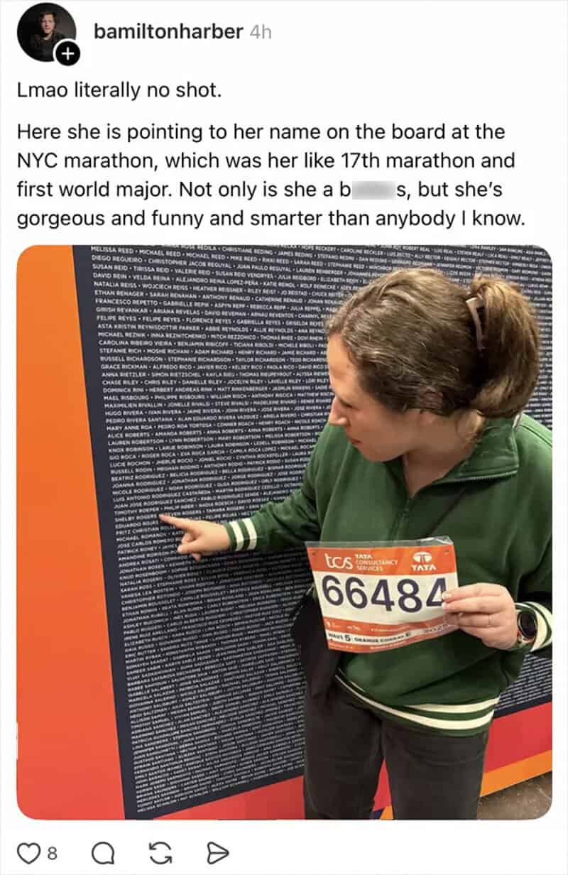 Woman pointing at her name on a marathon board, holding her bib number 66484.