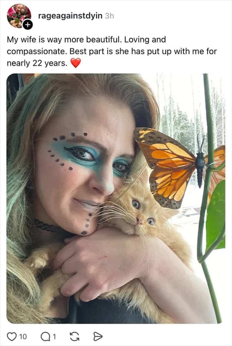 Woman with colorful makeup holding a cat and a butterfly on a plant.