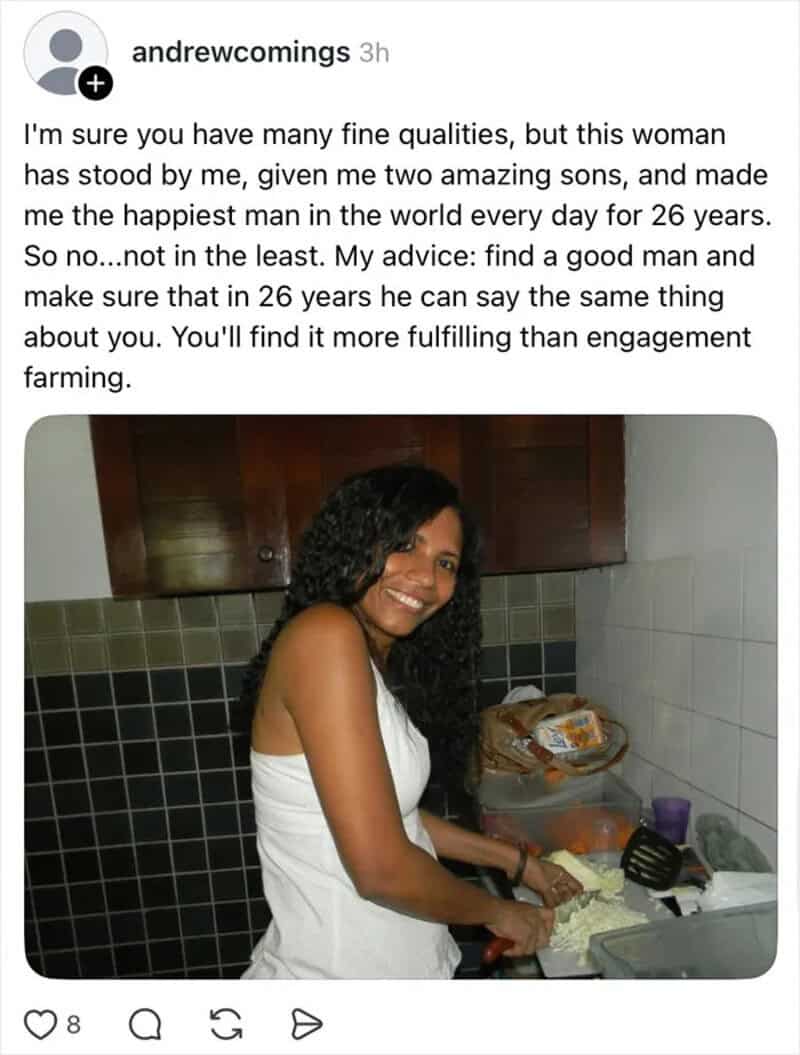 Woman with curly hair smiling in kitchen, preparing food.