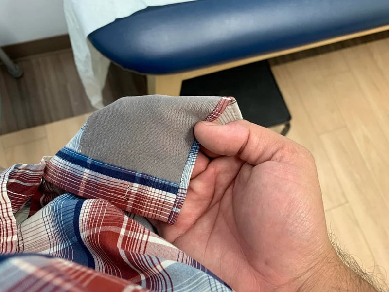 Close-up of a hand holding a folded plaid shirt with a hidden pocket.