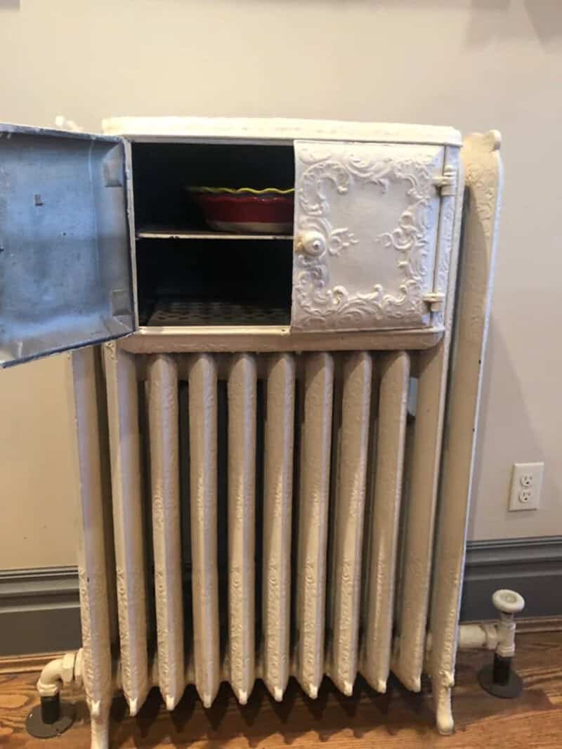 Vintage white radiator with a small cabinet on top, open door revealing shelves.