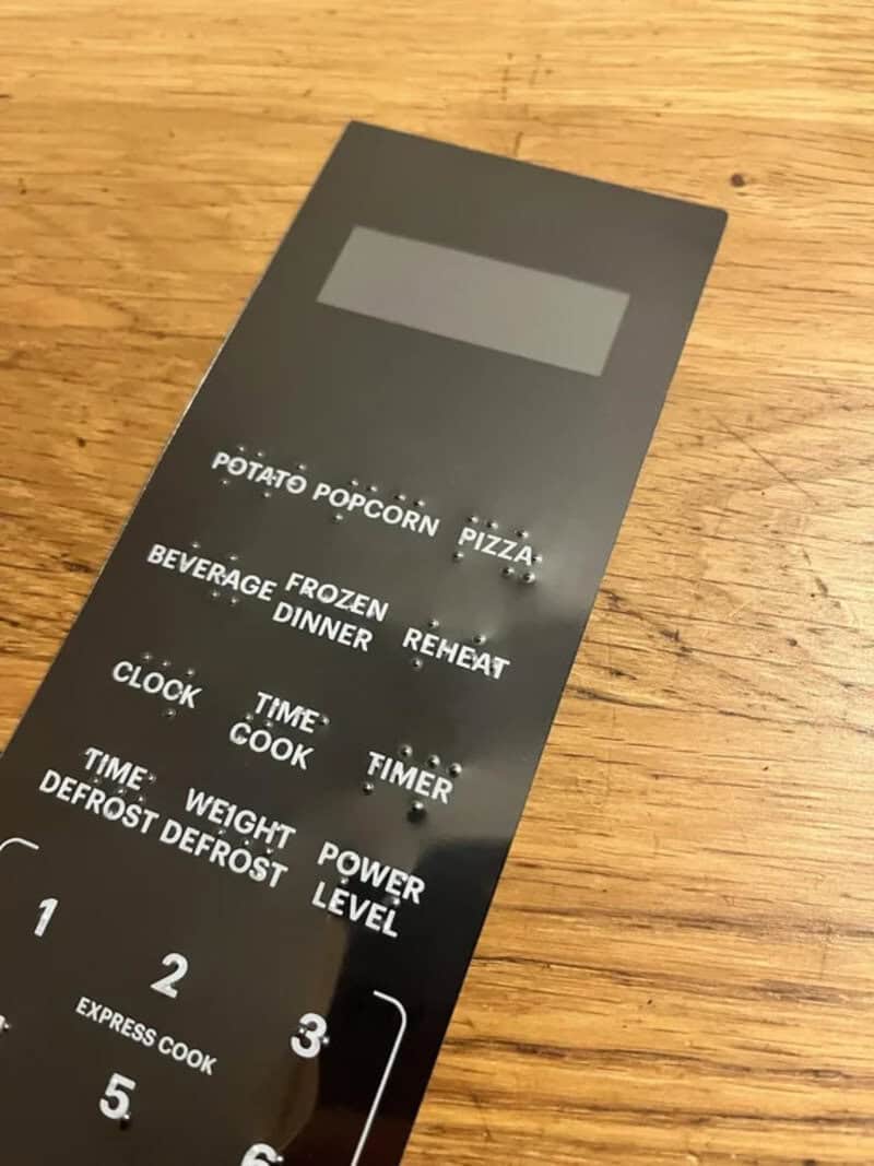 Black microwave control panel with buttons for various food items and functions.