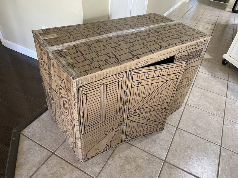 Cardboard box designed to look like a wooden cabinet with doors and a drawer.