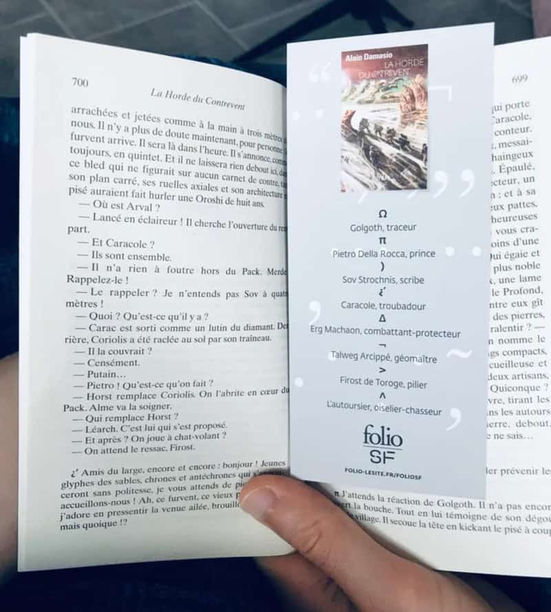 Open book with a bookmark and a hand holding it, showing a page with text and a small photo.