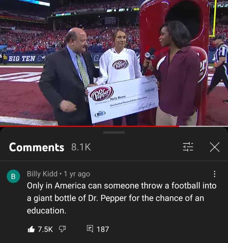 Person holding a large check on a football field with two other people, one with a microphone.