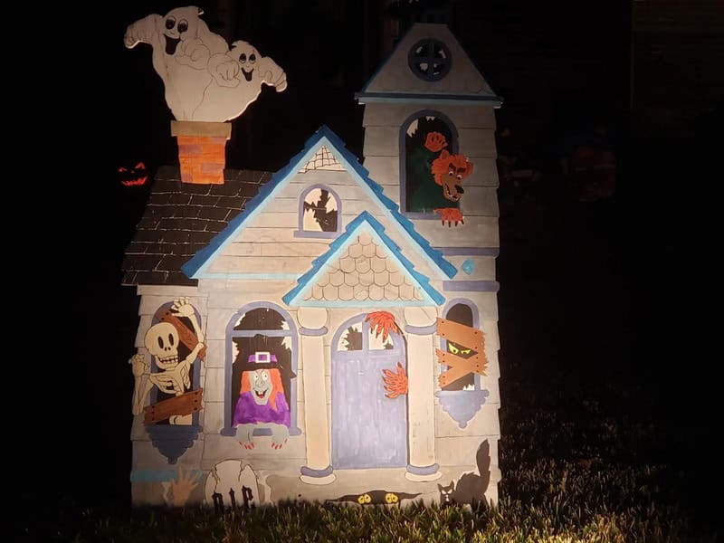 Halloween haunted house craft with cartoon ghosts, skeletons, pumpkin, and witch figures on a night.