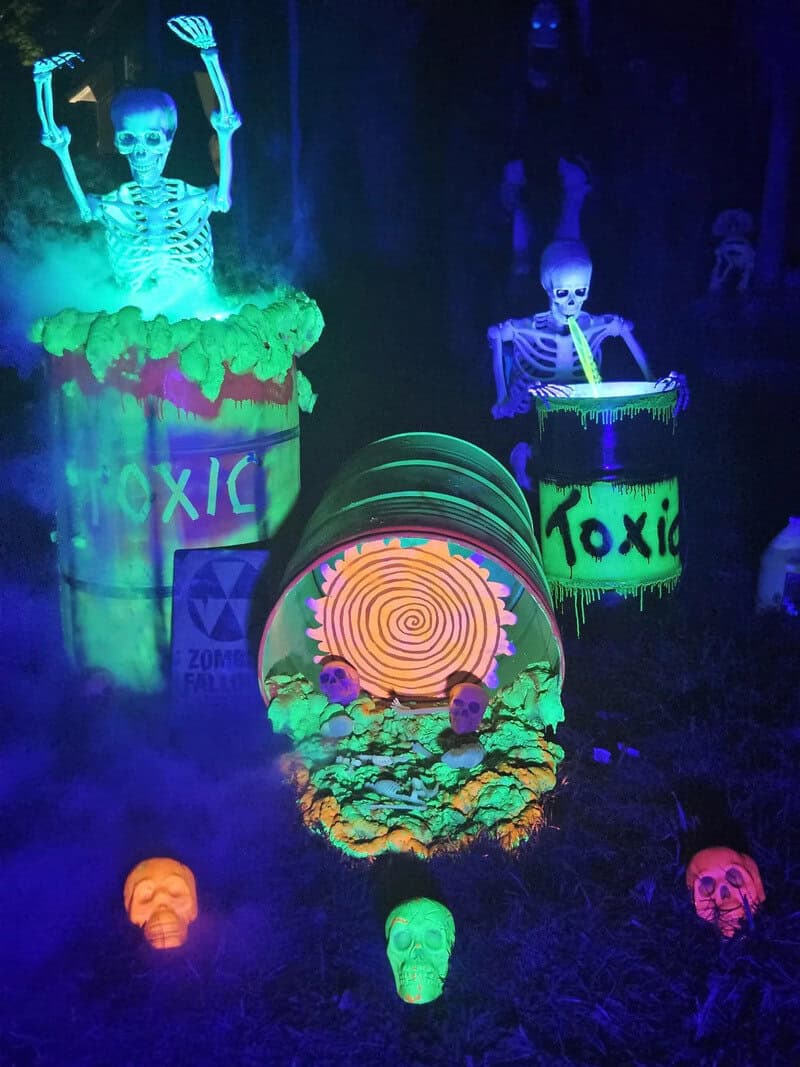 Halloween scene with glowing skeletons in barrels labeled 'Toxic' and a spiraled glowing tunnel and/.