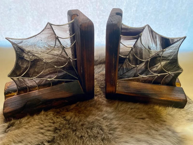 Dark wooden bookends shaped like spider webs, with intricate web patterns, resting on a furry brown/.