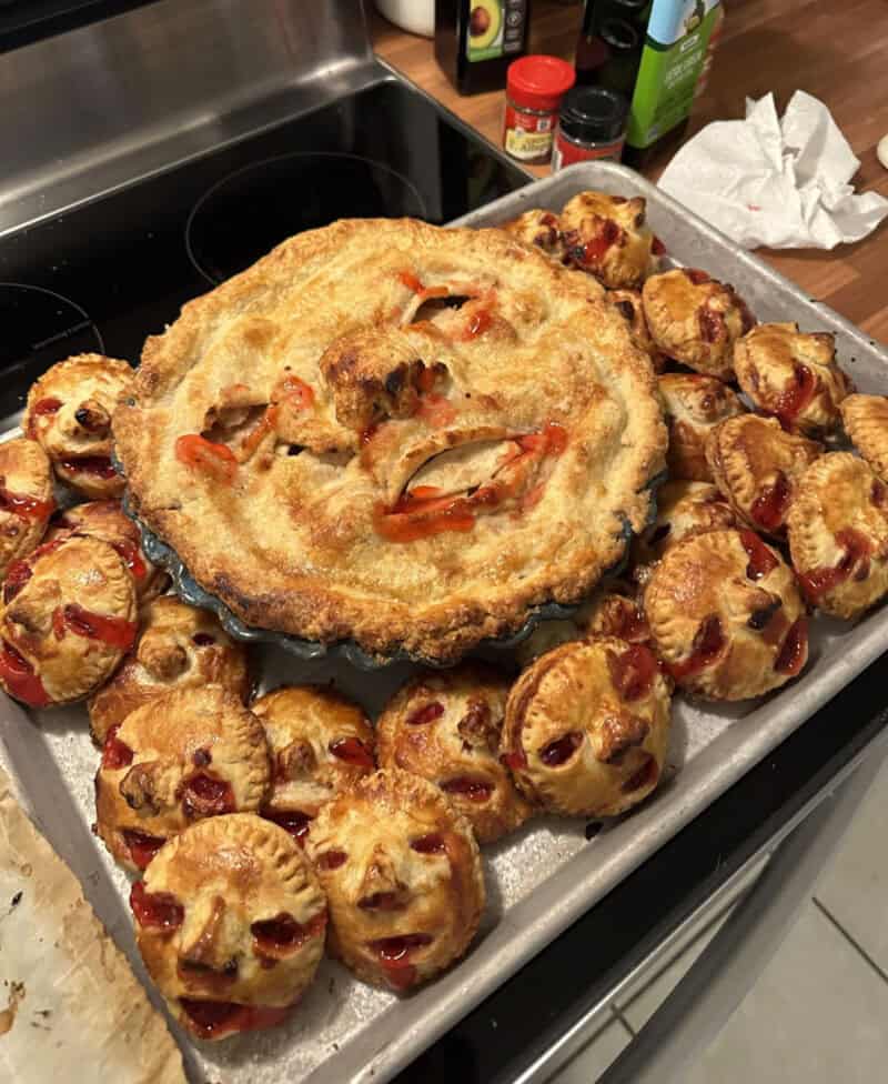 Halloween-inspired pie and bite-sized pastries on a baking sheet in a kitchen.