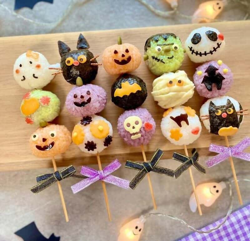 Assorted Halloween-themed cake pop ghosts, pumpkins, bats, and monsters on sticks with ribbons.