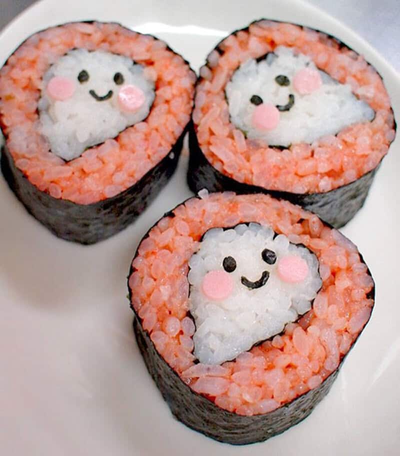 Sushi maki rolls with cute smiling faces made of white rice, pink cheeks, and orange outer layer.