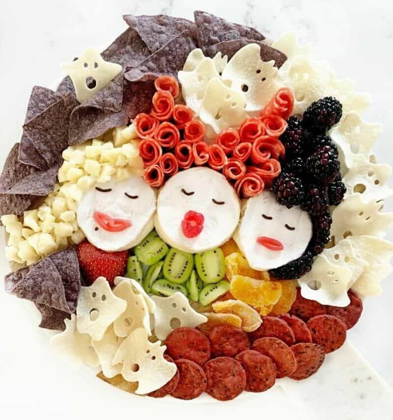 Three Halloween-themed faces made from fruits and snacks arranged as a festive platter, with ghost,叶.