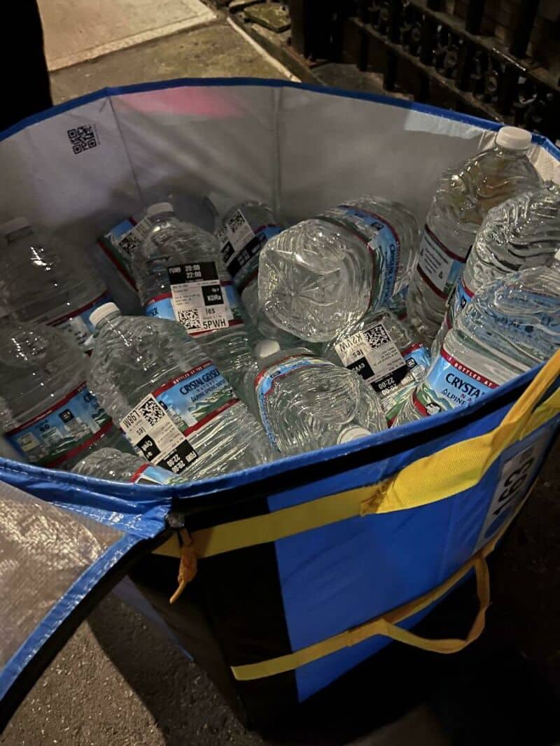 Cart filled with empty water bottles, some on the ground nearby.