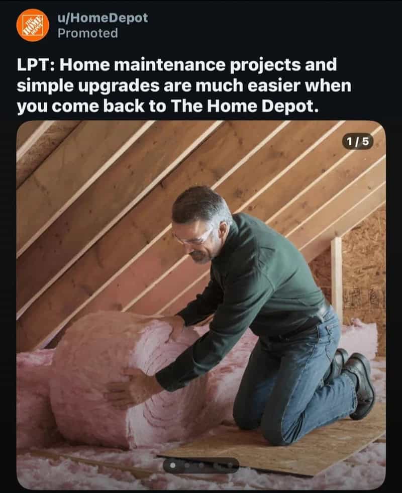 Man installing pink insulation in an attic with wooden beams.