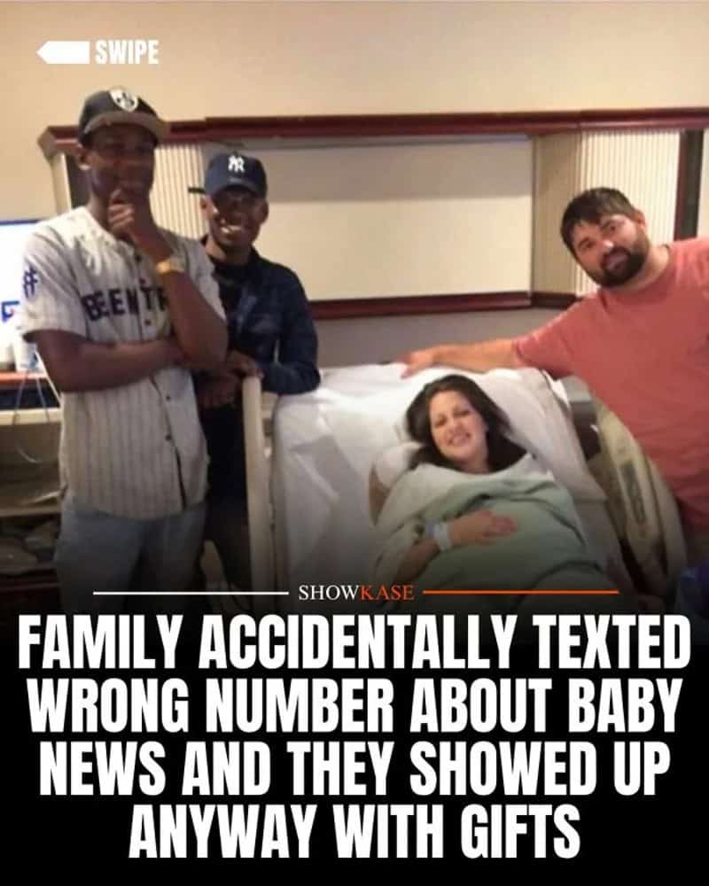 Family in hospital room, woman in bed, three men standing nearby, smiling.