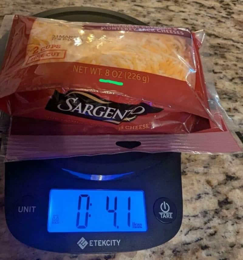 Package of Sargento shredded cheese on kitchen scale, showing 0:41 lbs.