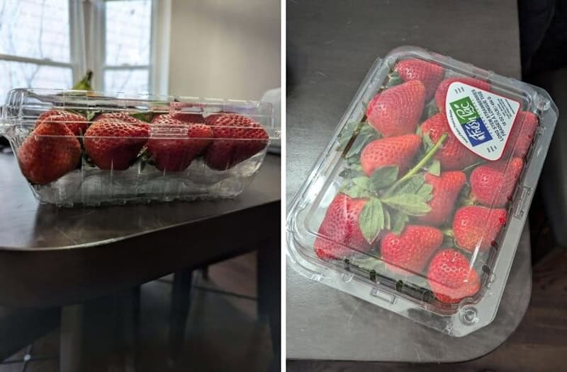 Fresh strawberries in clear plastic packaging on a table, with light from a window in the background.