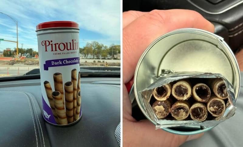 Pirouline dark chocolate wafer roll can on car dashboard, opened can showing filled chocolate sticks.