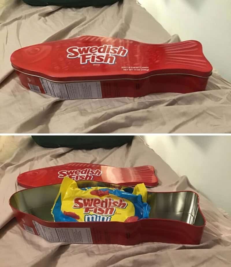 Red Swedish Fish candy tin with open lid showing yellow bag of Swedish Fish inside.