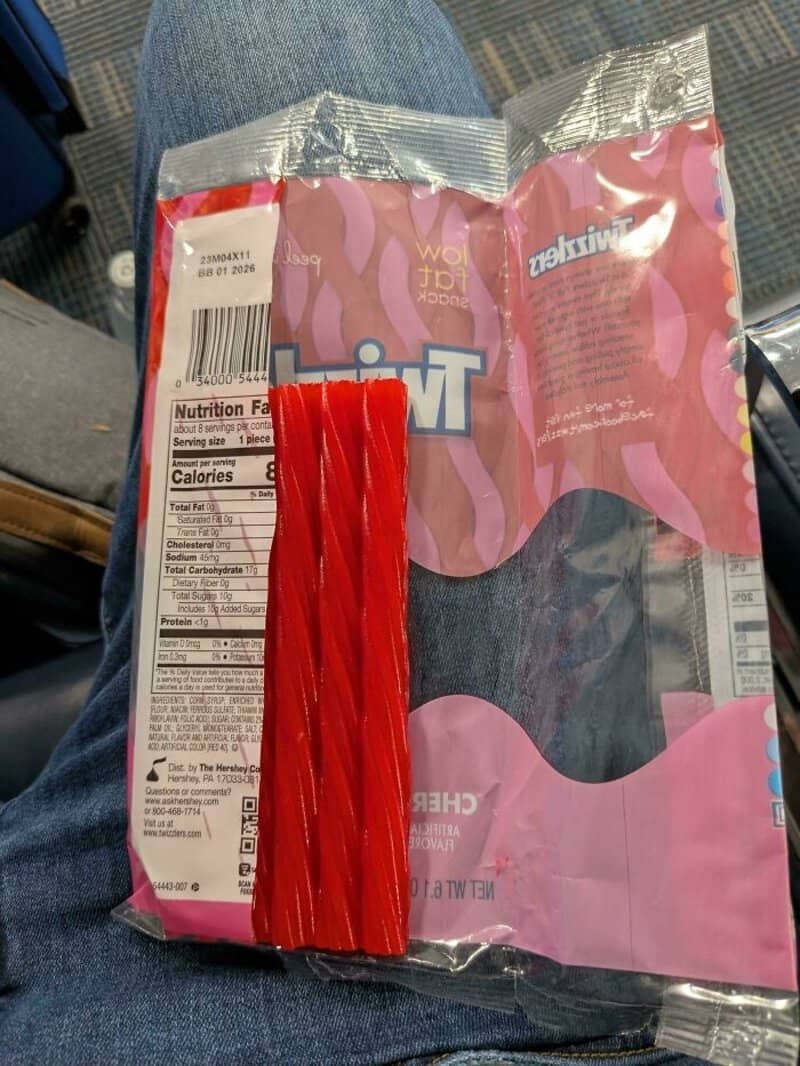 Flex candy pack with red licorice sticks exposed from pink and purple wrapper; damaged packaging and.