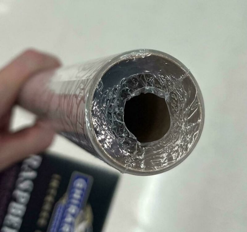 Close-up of a hollow cardboard core wrapped with metallic foil inside a tube.