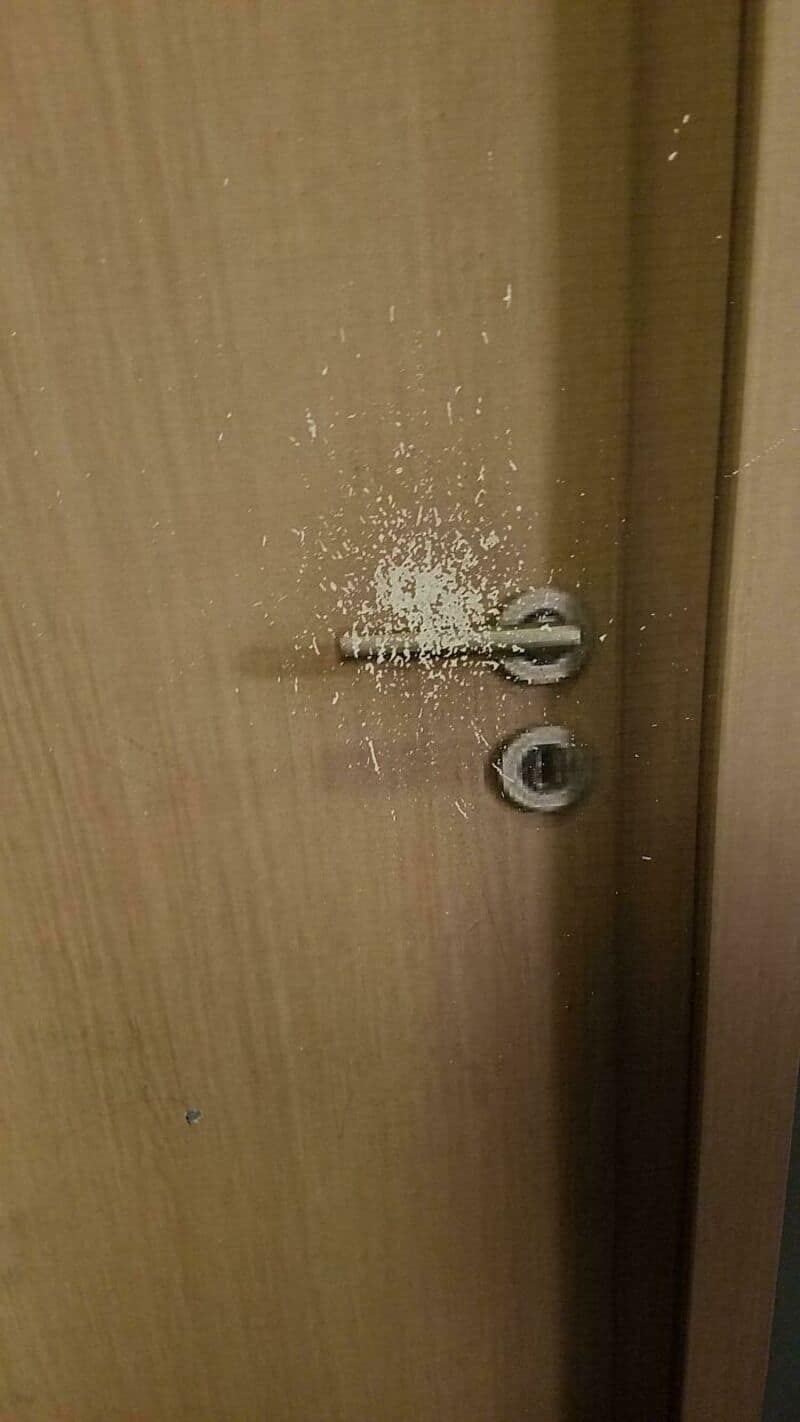 A door with a damaged lock and white powder scattered around it.