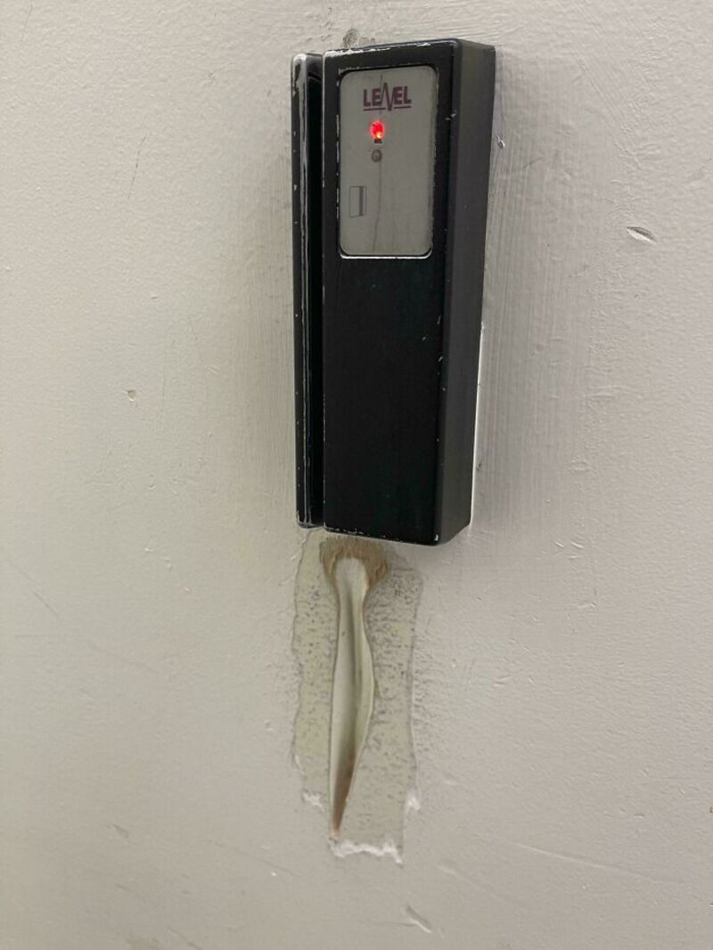 Black Level device on a wall with a red indicator light and a damaged cable.