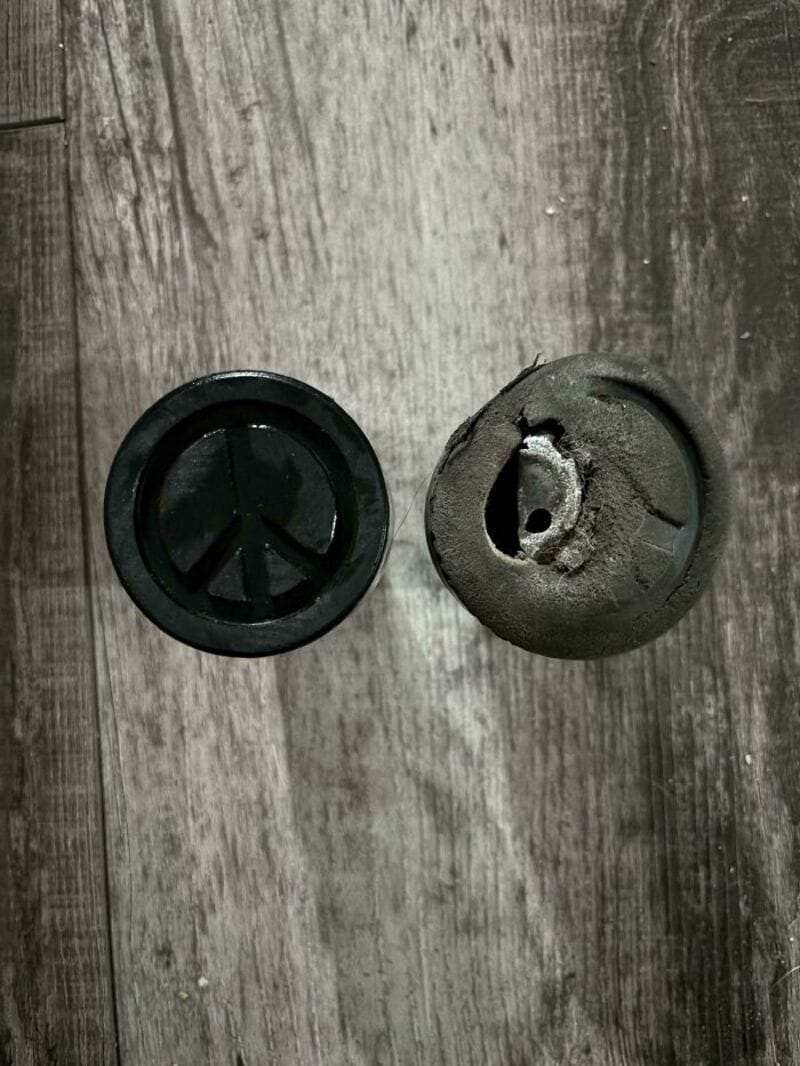 Two black rubber objects on a wooden surface, one intact and one damaged.