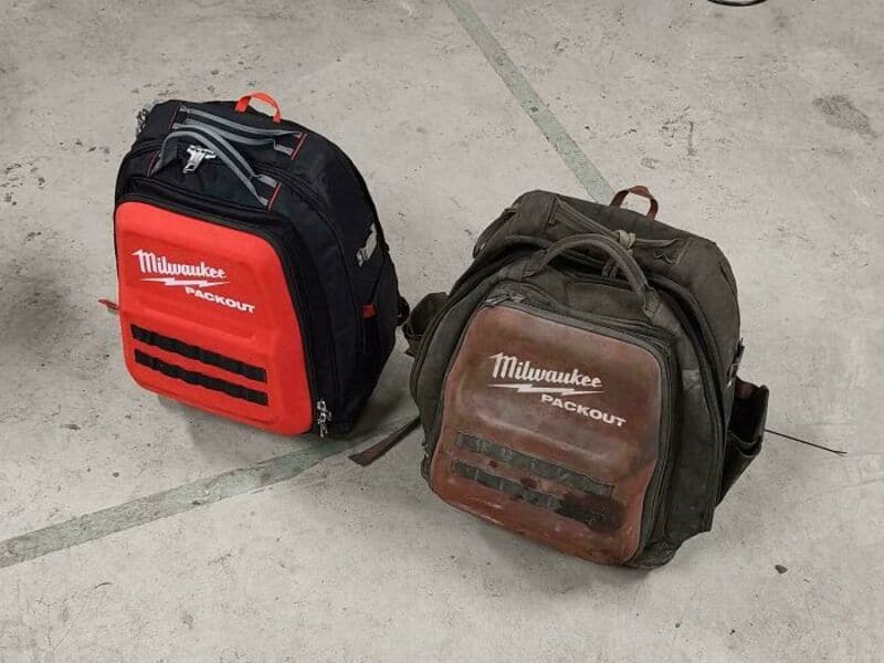 Two Milwaukee backpack bags on a concrete floor, one new and one worn.
