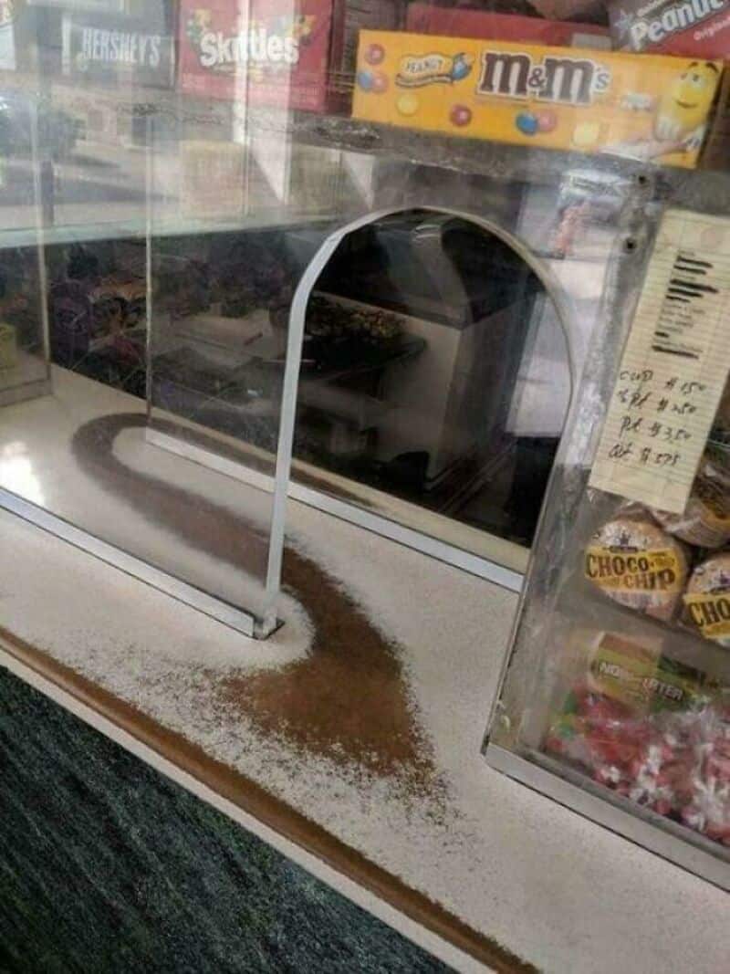 Empty snack display case with spilled powder and a mirror inside.