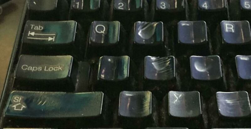 Close-up of a worn keyboard with shiny, scratched keys.