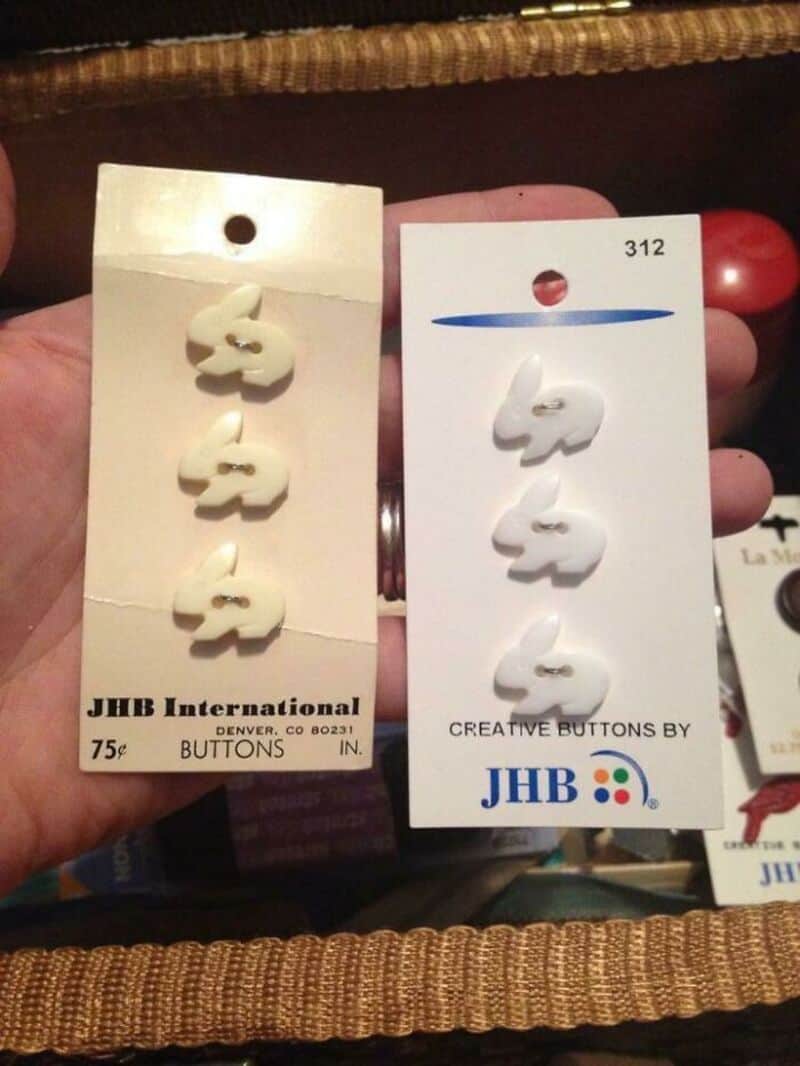 Two sets of white swan-shaped buttons on tags, one labeled JHB International and the other 312.