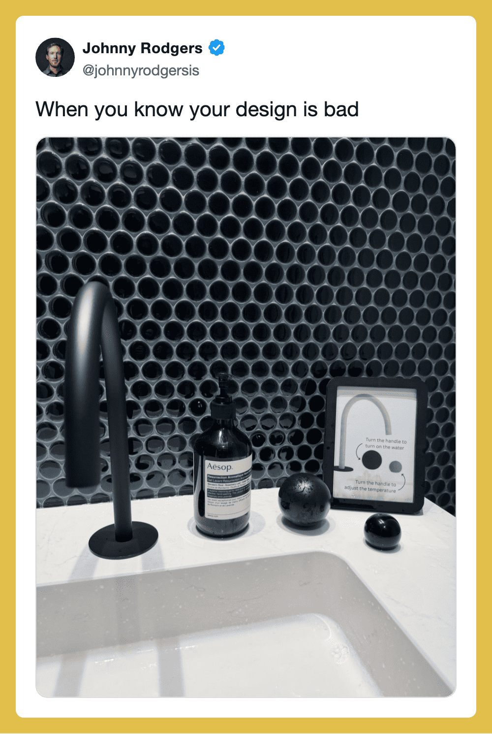 Bathroom sink with a black faucet, Aesop soap, and black decor against a honeycomb-patterned wall.