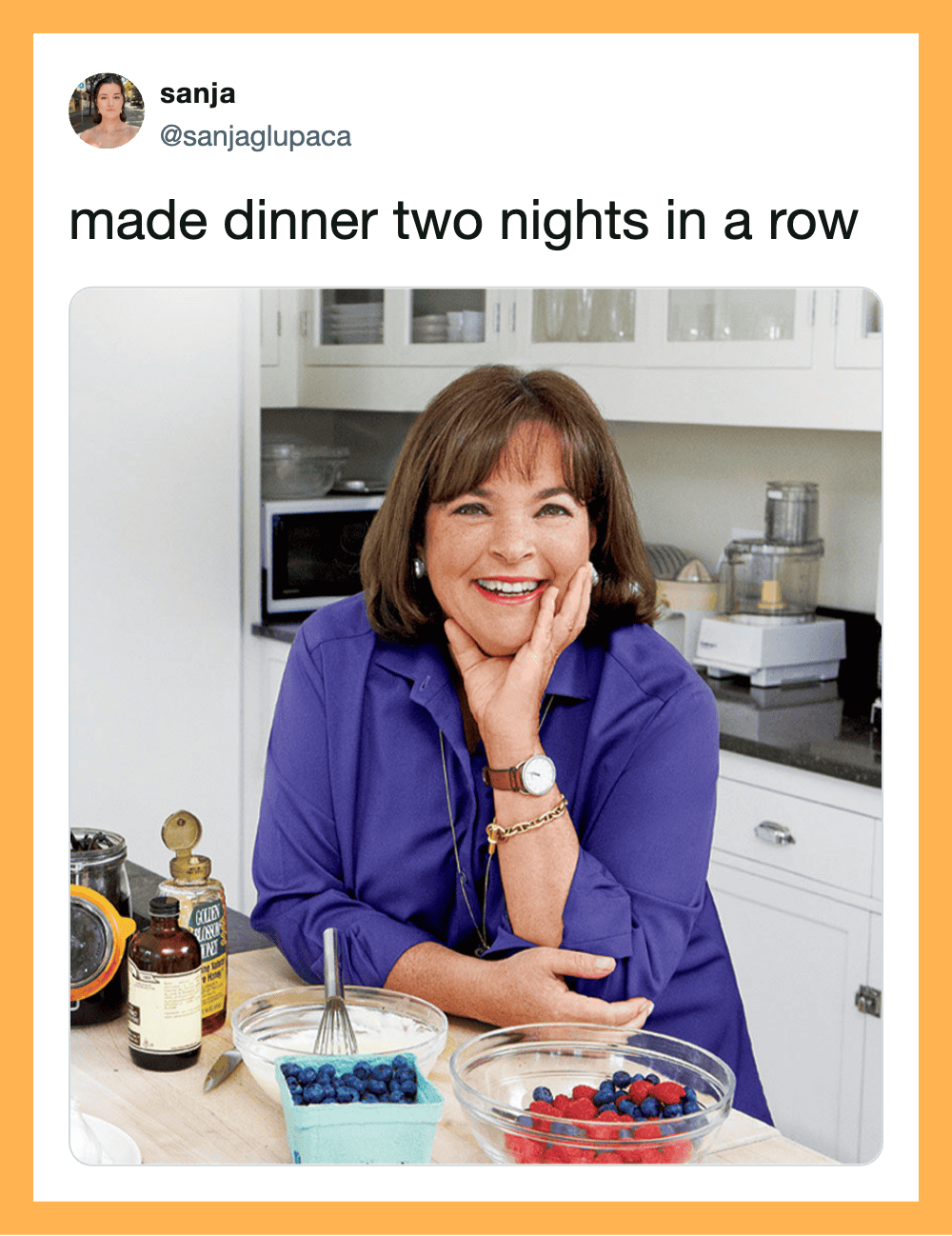 Woman smiling in kitchen with berries and supplements on counter.