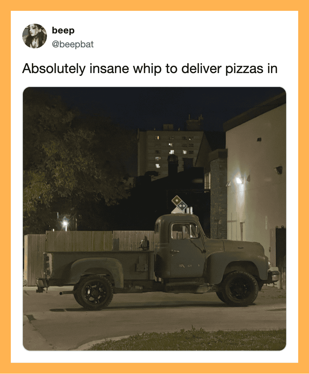 Green truck with Domino's pizza box on the back at night.
