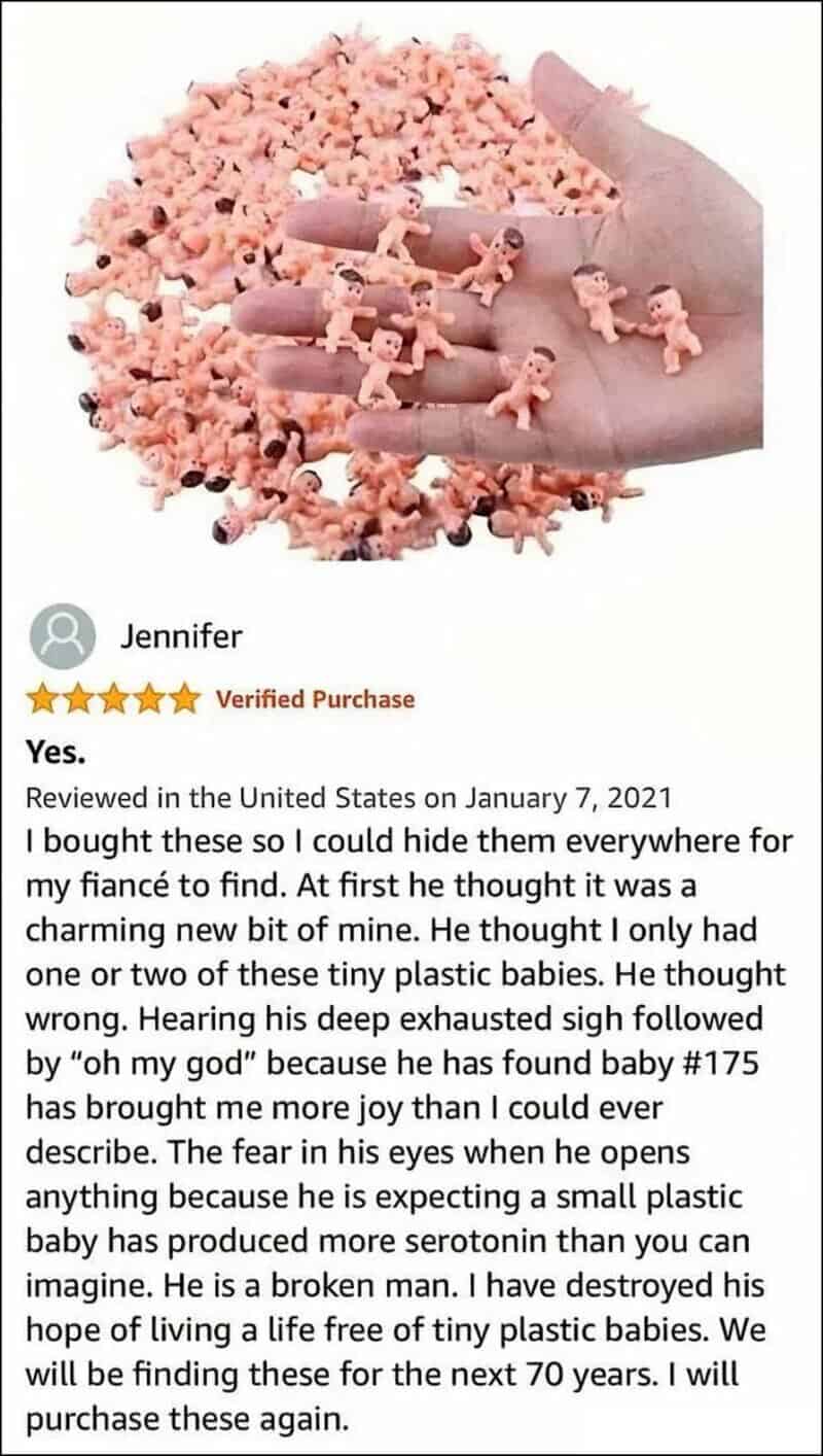 Hand holding tiny plastic baby figurines with a pile of similar figurines in the background.