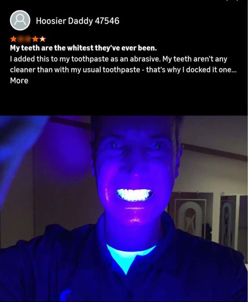 Person showing teeth under blue UV light, teeth appear very white.