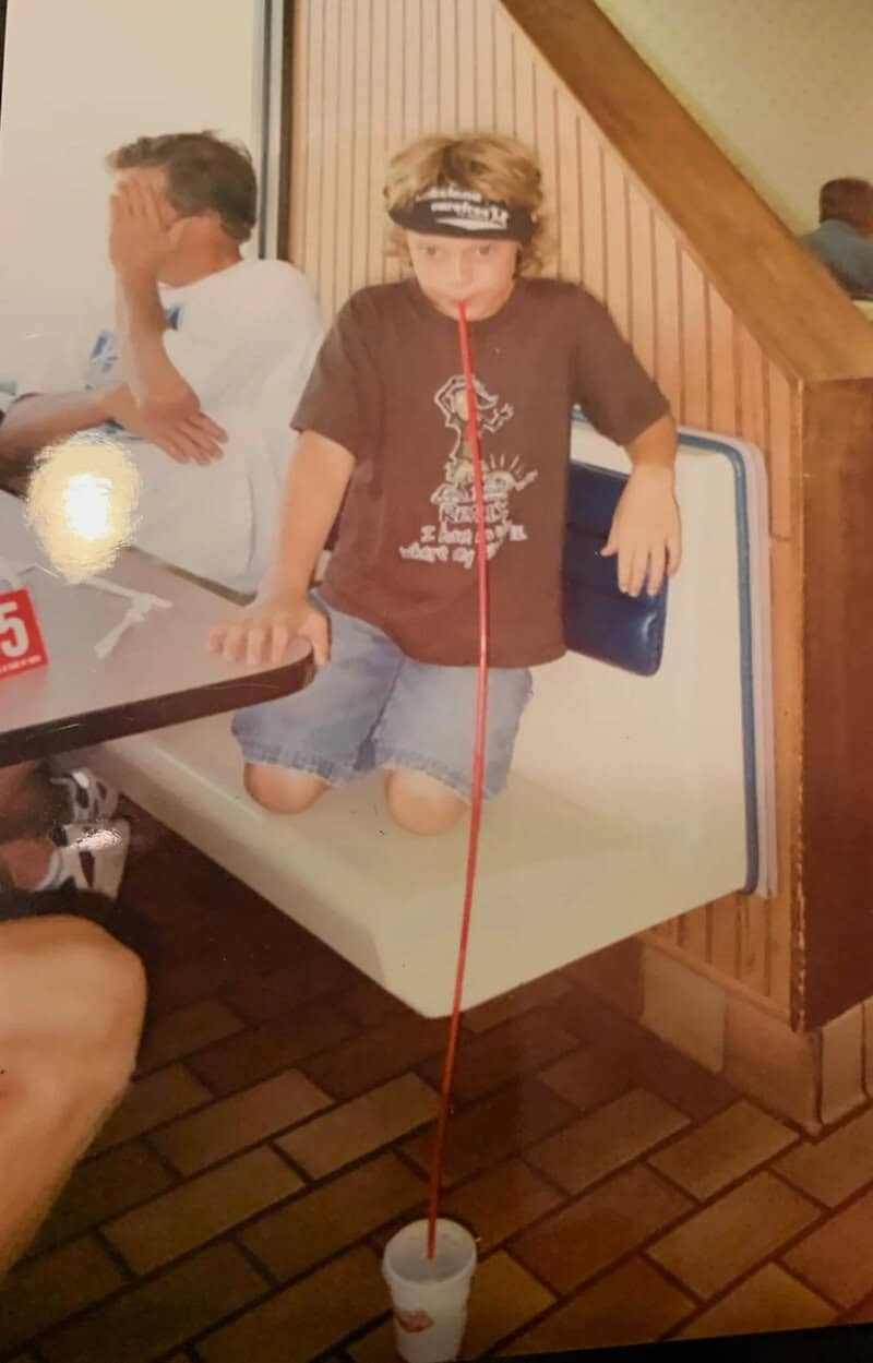 Child with a headband balancing a cup on a string in a restaurant.