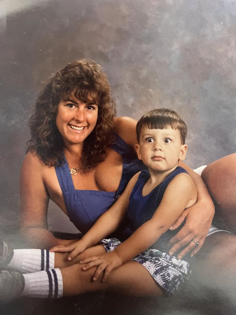 A woman with curly brown hair and a young boy with short dark hair, both in blue outfits, sitting on.