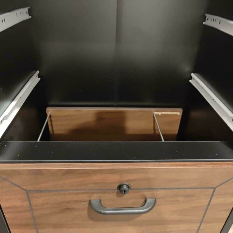 Drawer with a hidden compartment and a lock, part of a black and wood cabinet.