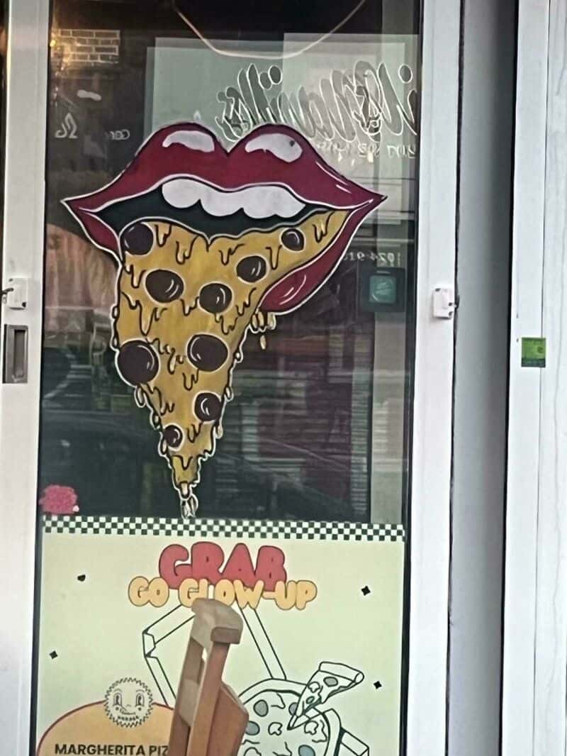 Pizza slice with lips and tongue, dripping cheese, on a window.