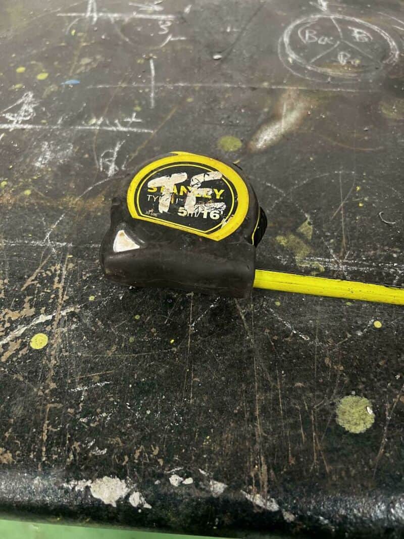 Tape measure on a scratched, paint-splattered surface.