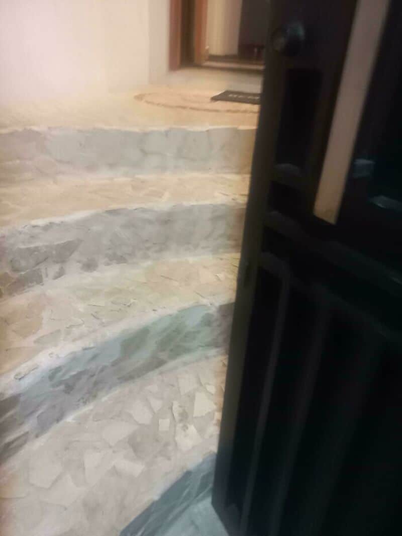 Staircase with uneven steps and a door partially blocking the view.
